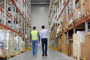 Poster - logistic business, shipment and people concept - rear view of businessman and worker walking along warehouse