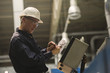 © PhotoAlto - Factory worker examining control panel