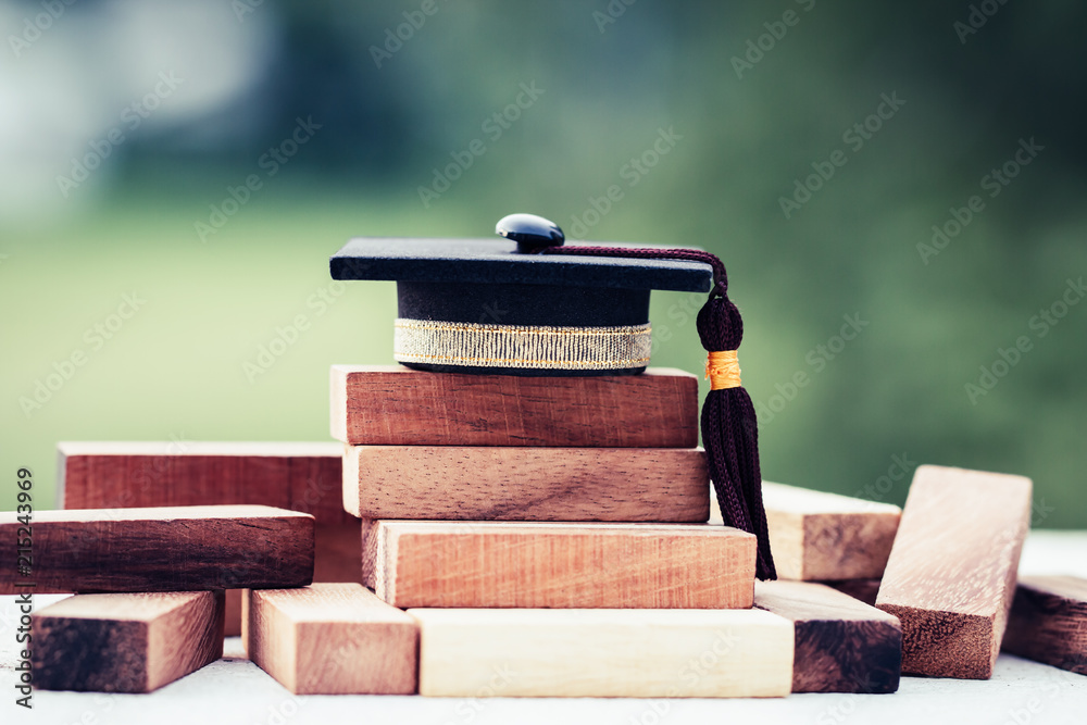 Graduation celebrating cap on wooden square blocks tower. Blank space ...