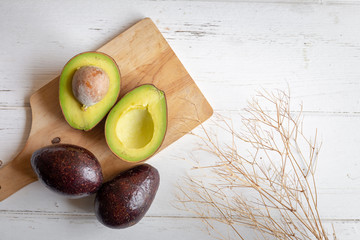 Fresh organic avocado sliced in half on white wooden table