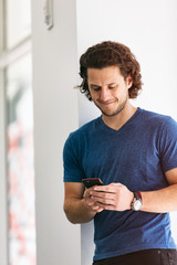 Wall Mural - Workspace: Handsome Guy Using Cell Phone In Brightly Lit Hallway