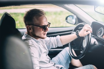 Wall Mural - blonde male business car driver in sunglasses.