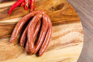 Wall Mural - Uncooked chilli beef sausages on chopping board