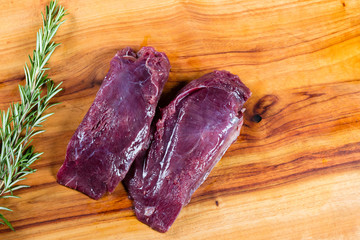 Raw kangaroo meat slices on chopping board