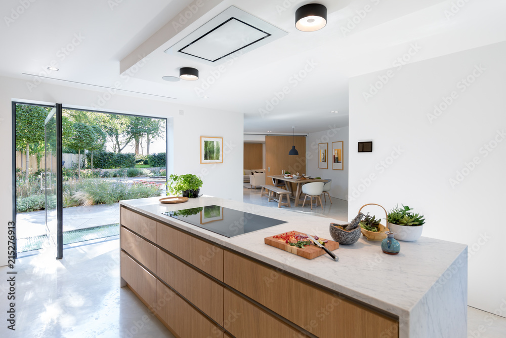View of modern kitchen counter looking through to dining area. Glass exterior doors with views to the garden.