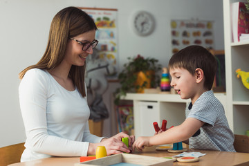 Wall Mural - Teacher and child playing with didactic colorful toys indoors - preschool