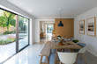 © Phillips Visuals/Stocksy - Contemporary dining room with views to the garden through large glass areas. Table set for lunch.