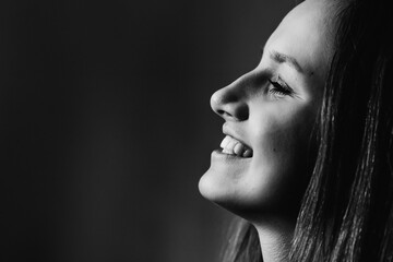 close-up profile face of a beautiful girl who smiling on black and white photo