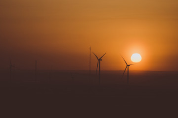 Wind turbines against a background of sunset and orange sky 