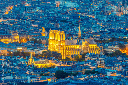Obraz Dibond Nocny widok na Notre Dame de Paris z panoramicznego tarasu Tour Montparnasse. Zbliżenie kościoła gotyckiego Notre Dame najważniejszy zabytek religijny stolicy Francji. Panoramę miasta Paryża.