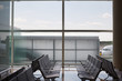 © Miquel Llonch/Stocksy - Airport hall with empty seats and big window with a view