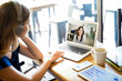 © AntonioDiaz - Freelancer with laptop taking a video call at a cafe and working
