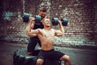 © zamuruev - Two muscular athletes training, one raise, push the barbbell when other is motivating. Scream. Working hard. Street gym. Exercise for the shoulder muscles, deltoid.