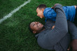 © Rob and Julia Campbell/Stocksy - Father and son lying on football field, laughing