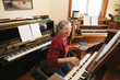 © Rob and Julia Campbell/Stocksy - Happy mature woman playing piano and organ in home studio
