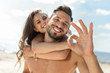 © LIGHTFIELD STUDIOS - selective focus of man showing ok sign and piggybacking his girlfriend