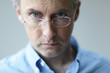 © Marcel/Stocksy - Man with stern look over his glasses