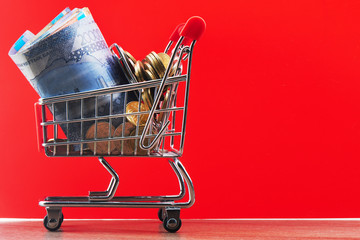 Tenge. Kazakhstan money in shopping cart on red background close up..