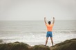 © Wavebreak Media - Man standing with his raised hand on the beach