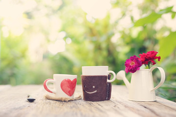 Wall Mural - Heart pattern cup and smiling face cup with flower pot on wooden table