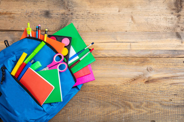 Wall Mural - Blue backpack full of school supplies on wooden background, top view, copy space