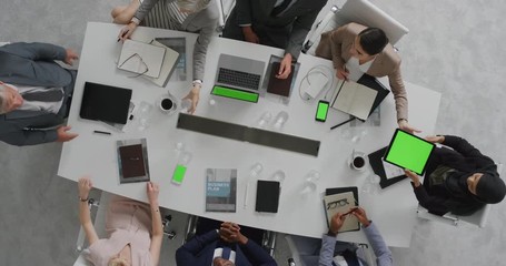 Wall Mural - multi ethnic business people brainstorming innovative ideas viewing chroma key using mobile computer technology in boardroom meeting overhead