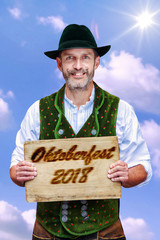 Wall Mural - bavarian man holding a sign with the words Oktoberfest 2018