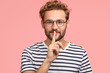 © wayhome.studio  - Let`s keep it in secret! Handsome hipster makes shh gesture as spreads rumors, shows hush sign with index finger, dressed casually, isolated over pink background. People, secrecy, conspiracy concept