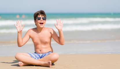 Young child on holidays at the beach very happy and excited, winner expression celebrating victory screaming with big smile and raised hands