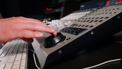 Wall Mural - Sound designer rotates the scroll wheel on mixing console in a professional recording studio. Musician working on new song. Slow motion. 4k