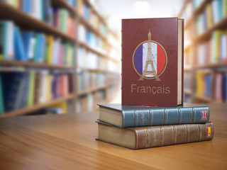 Poster - Learn French concept. French dictionary book or textbok with flag of France and Eiffel tower on the cover in the library.