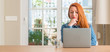 © Krakenimages.com - Redhead woman using computer laptop at home serious face thinking about question, very confused idea