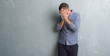 © Krakenimages.com - Young caucasian man over grey grunge wall with sad expression covering face with hands while crying. Depression concept.