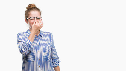 Canvas Print - Young blonde business woman smelling something stinky and disgusting, intolerable smell, holding breath with fingers on nose. Bad smells concept.