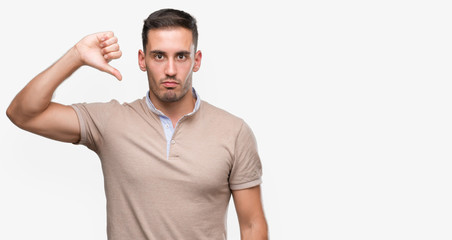 Wall Mural - Handsome young man with angry face, negative sign showing dislike with thumbs down, rejection concept