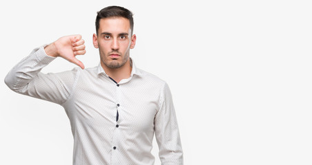 Wall Mural - Handsome young business man with angry face, negative sign showing dislike with thumbs down, rejection concept