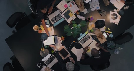 Wall Mural - multi ethnic business people working late planning strategy for corporate project developing creative ideas in messy boardroom top view