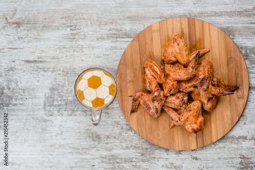 Fotografía beer mug with a football on a beer foam near fried chicken wings