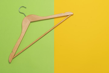 A wooden clothes hanger on a green and yellow background