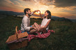 Portrait of young couple having good times on a picnic date, behind them is a beautiful sunset over Boka Bay