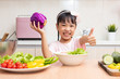 Leinwandbild Motiv Asian Chinese little girl making salad in the kitchen