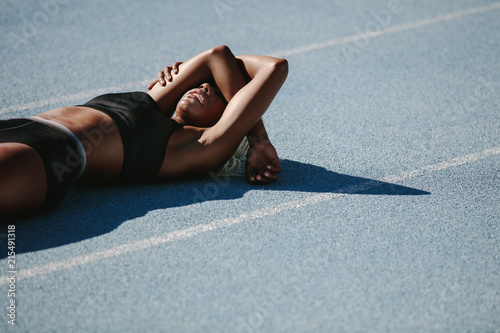 Cuadros en Lienzo Female athlete relaxing on running track after workout