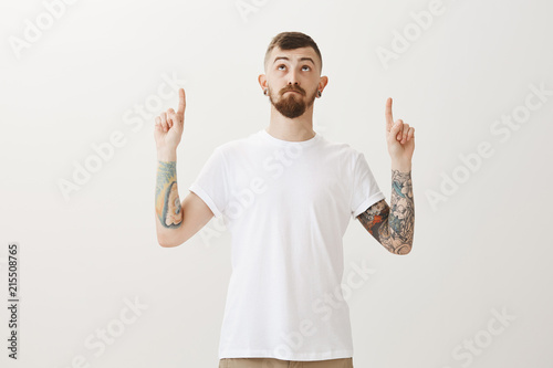 Fotomural Handsome stylish caucasian urban guy with beard and tattoos, pointing and lookin