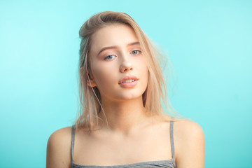 caucasian student girl smiling, being in positive mood looking at camera over blue background.