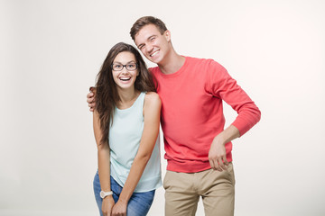 Happy young lovely couple standing together and laughing. Studio shot over white background. Friendship, love and relationships concept