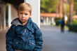 © pavel_shishkin - Sad lonely and frustrated handsome little boy lost and standing near a pillar with his hands in his pockets in the city park.