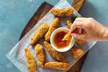 Wall Mural - Man eating chicken breast nuggets sour sweet sauce top view