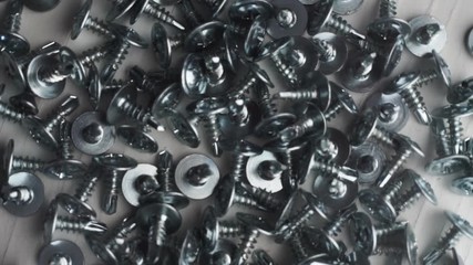 Poster - Macro screws rotating on a metal table and black background. Seamless loop.