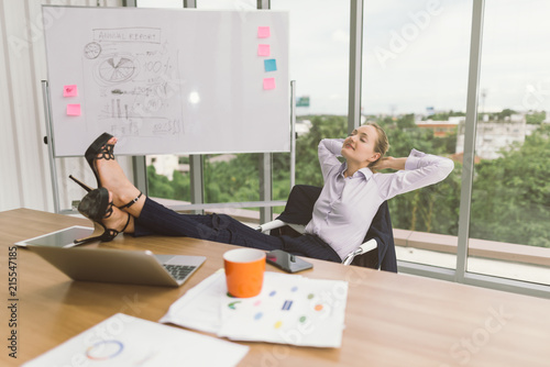 Businesswoman Relaxing With Feet Up At Desk In Creative Office Businesswoman Relaxing With Feet Up At