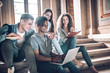 © HBS - Students are studying together.Multiethnic group of young people looking at a laptop and and sitting on steps in university hall.